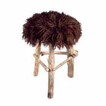Stool with legs made out of brances and the seat covered with a brown Icelandic sheepskin